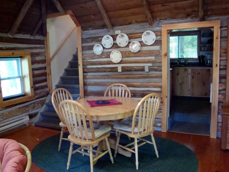 Log dining area showing entrance to ktichen and stairs to bedroom